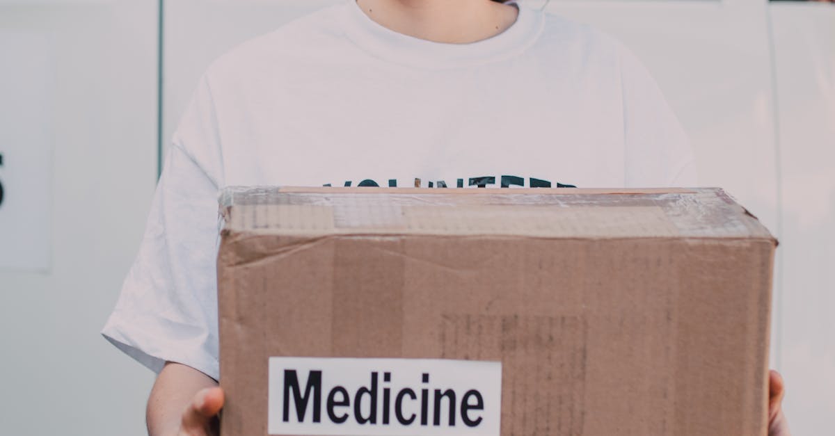 A smiling female volunteer holding a donation box labeled 'Medicine' in front of a van.